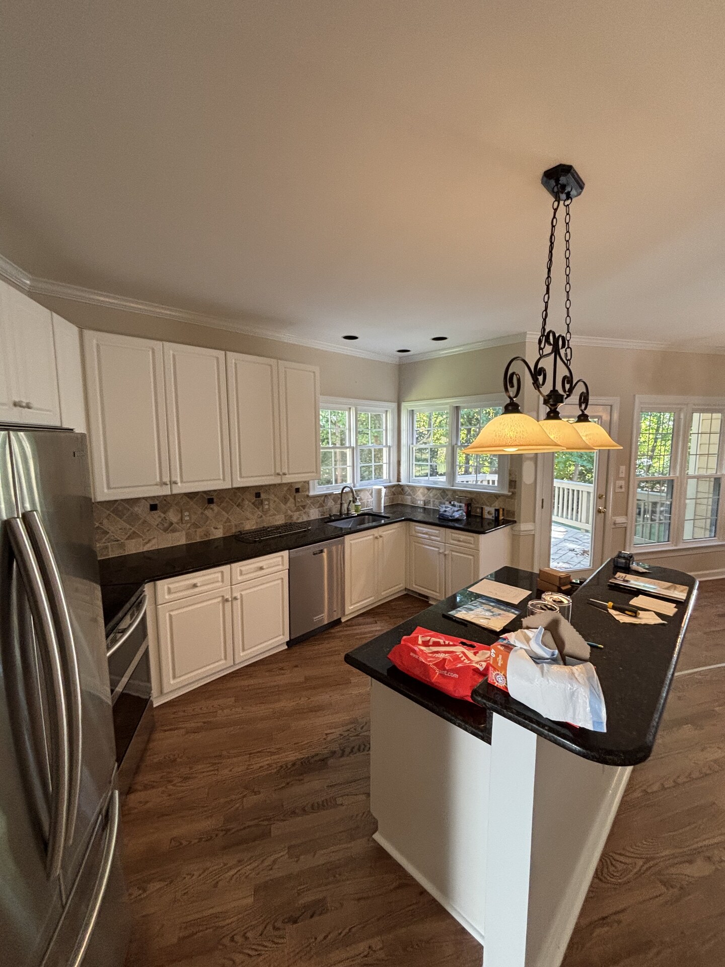 Kitchen with white cabinets, granite counters, and a center island before interior demolition