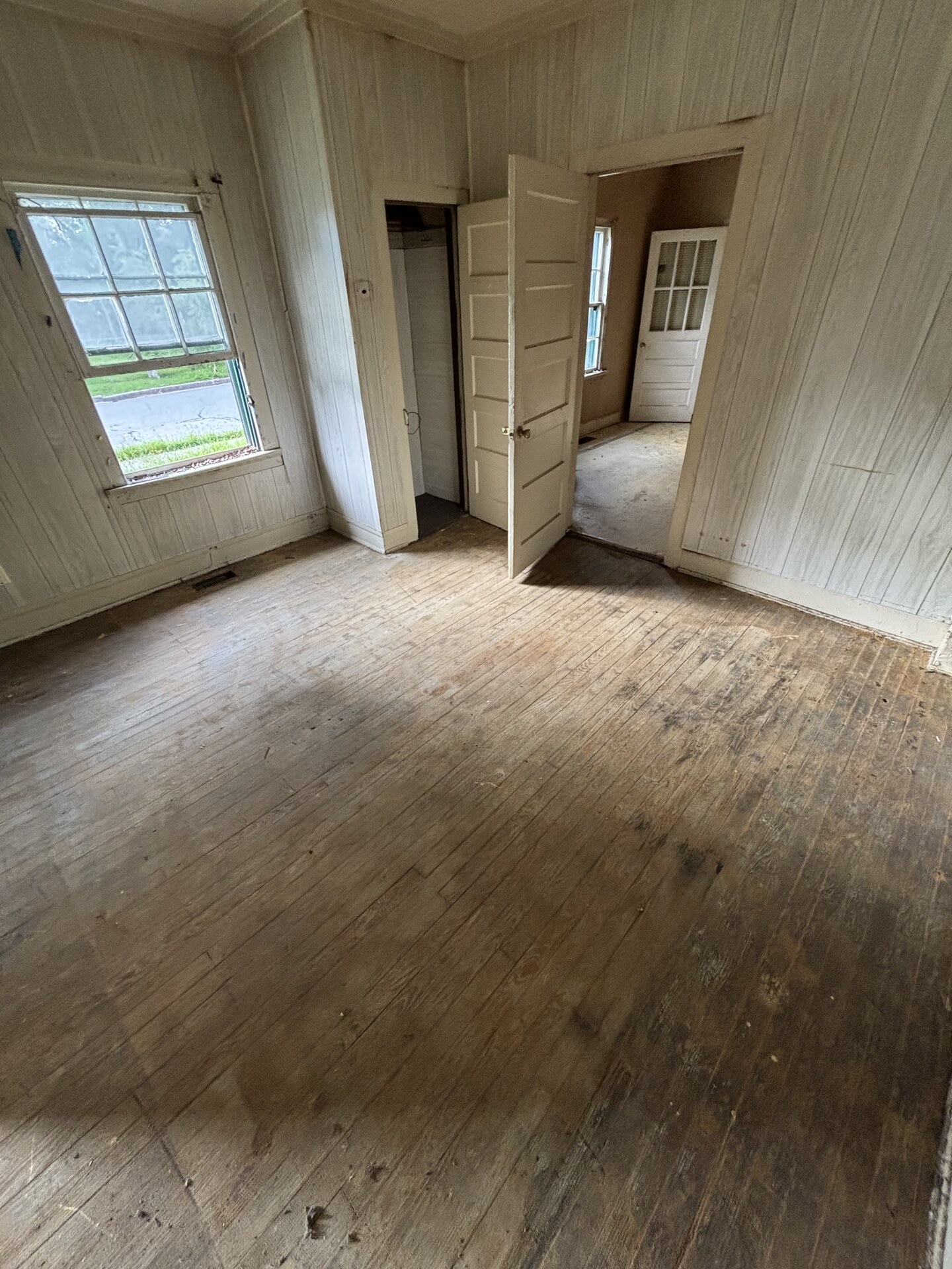 The same home emptied of furniture and junk, with bare wood floors and an open doorway